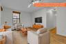 Bright living space featuring hardwood flooring, a large window with wood-finish blinds, track lighting, and a neutral wall palette