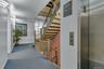 Staircase featuring decorative metal balusters and wood handrails and third floor elevator landing