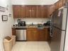 Kitchen featuring wood-finish cabinetry, granite-style countertops, stainless steel refrigerator, stainless steel dishwasher, and tile flooring