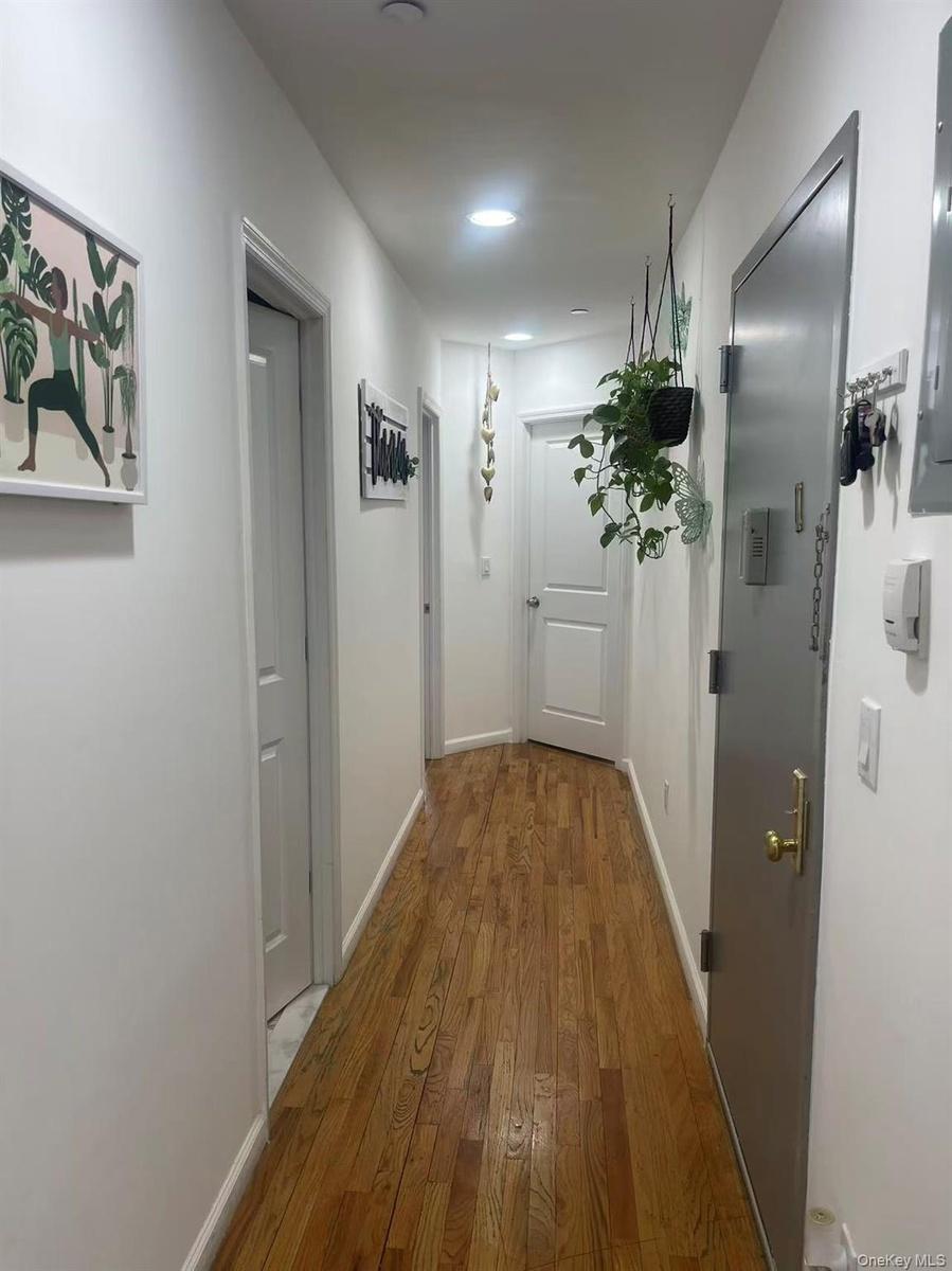Hallway featuring wood-finish flooring, white walls, and recessed lighting