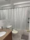 Bathroom featuring a built-in tub with a shower fixture, white ceramic toilet, and a vanity with a granite-look countertop and integral sink