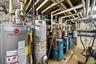 Utility room featuring multiple water heaters and a series of blue heating units