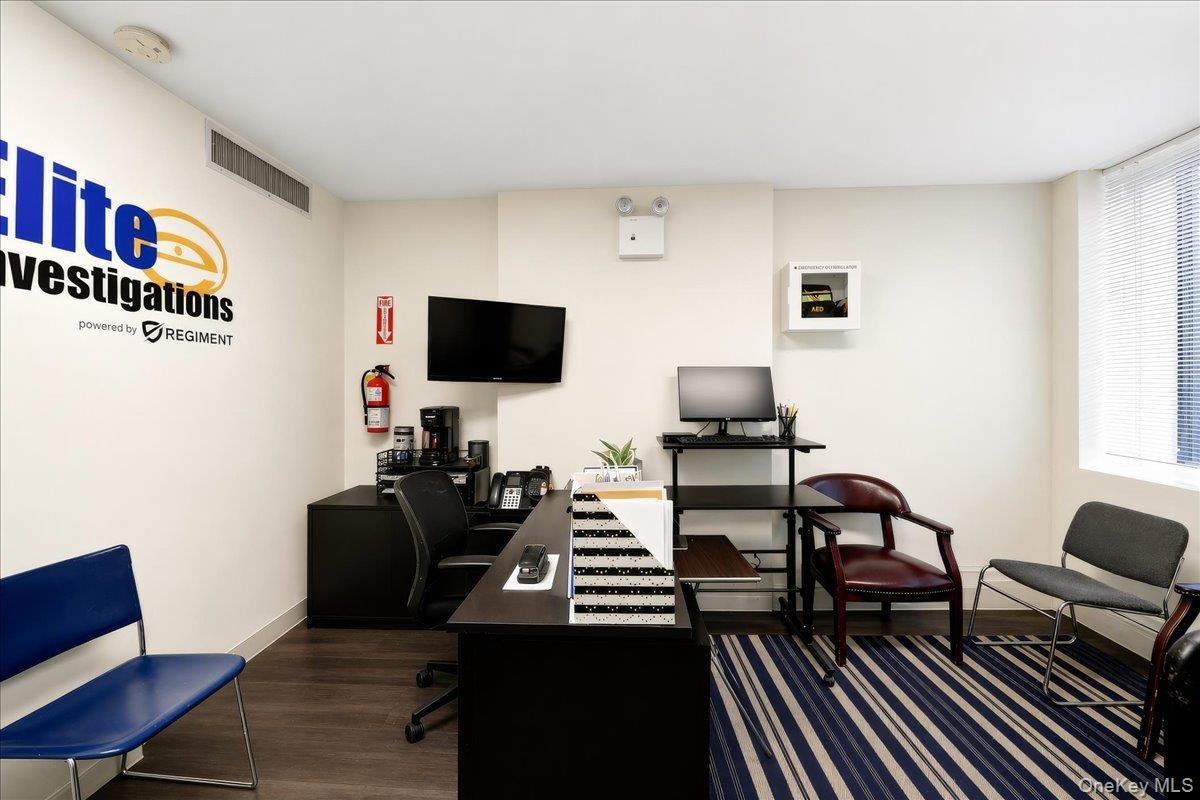 Reception area featuring wood-finish flooring, light-toned walls, and a window with blinds