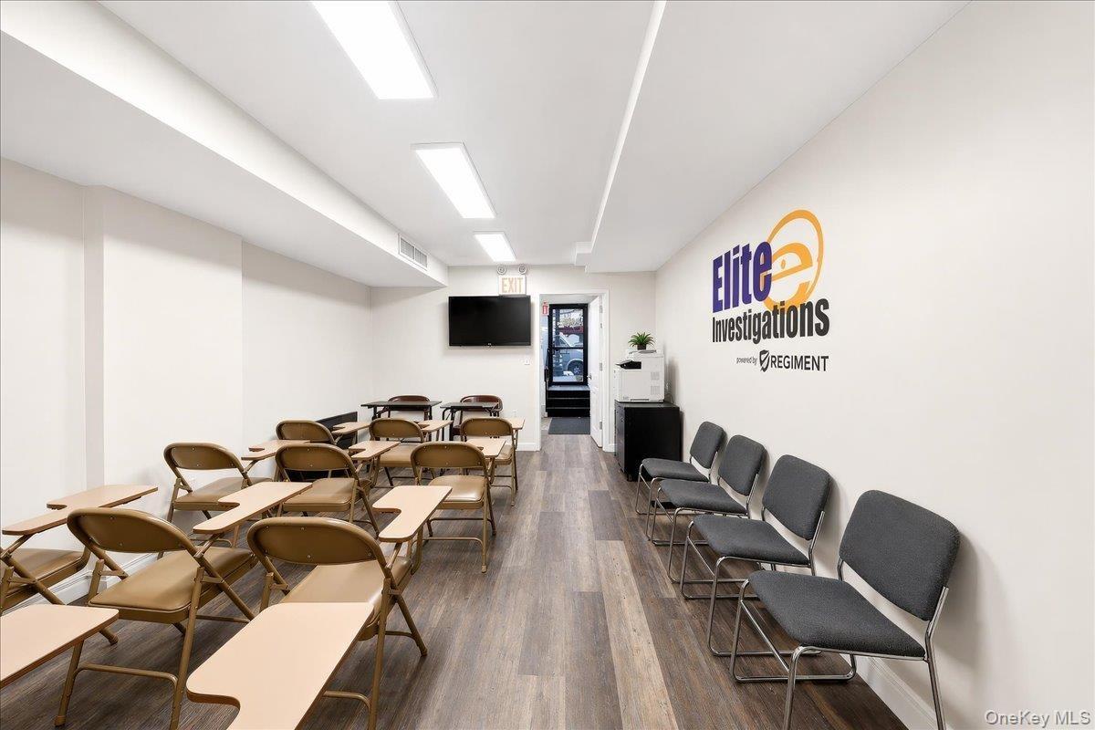 Spacious room featuring wood-finish flooring, recessed lighting, and a wall-mounted flat-screen display