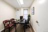 Dedicated office space featuring wood-finish flooring, neutral-toned walls, a window with horizontal blinds, a white door with a lever handle, and rec