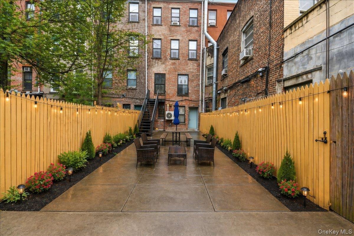 Paved patio with string lighting and planted garden beds Virtually Staged