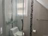 Shower enclosure featuring glass door, tiled walls with decorative mosaic accent, and integrated glass shelving