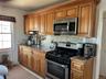 Kitchen featuring wood cabinetry, stainless steel appliances, a tile backsplash, and a double basin sink