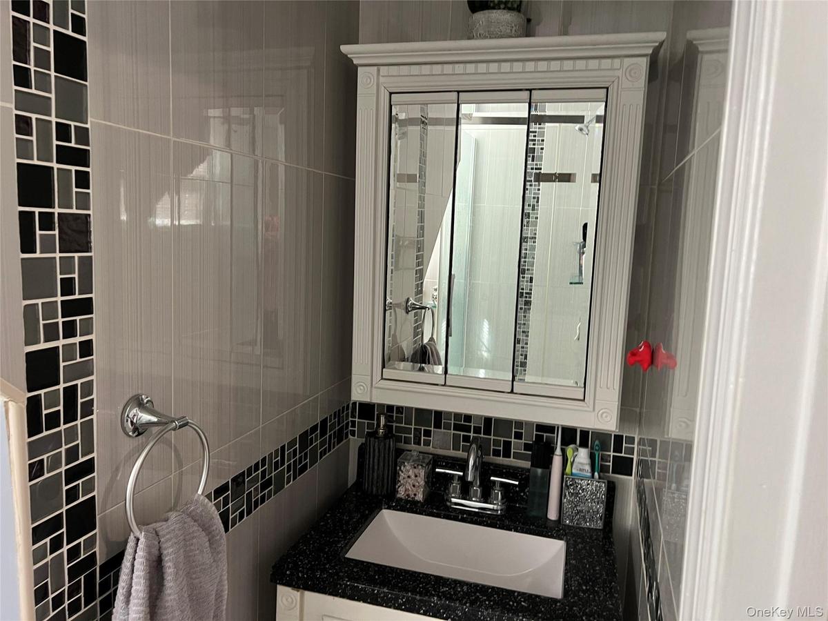 Bathroom with a white vanity, black speckled countertop, and an integrated white sink