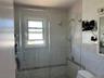 Walk-in shower enclosure featuring clear glass panels, a chrome showerhead with an attached handheld spray, and a tiled surround
