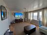 Living space featuring wood-finish flooring, a contemporary chandelier, and multiple windows providing natural light