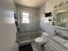 Walk-in shower with clear glass enclosure, a rainfall showerhead, and a handheld spray