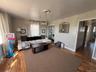 Living area featuring wood-finish flooring, a contemporary ceiling light fixture, and a neutral color palette