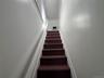 Staircase featuring dark carpeted treads, white painted risers, and white baseboards