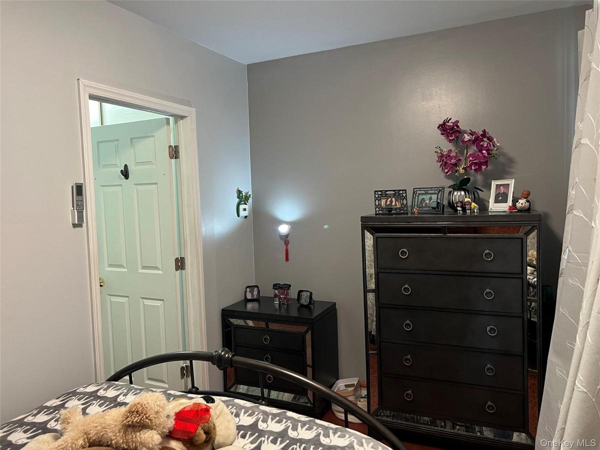 Interior room featuring light gray walls, a white paneled door with dark hardware, and a dark metal bed frame