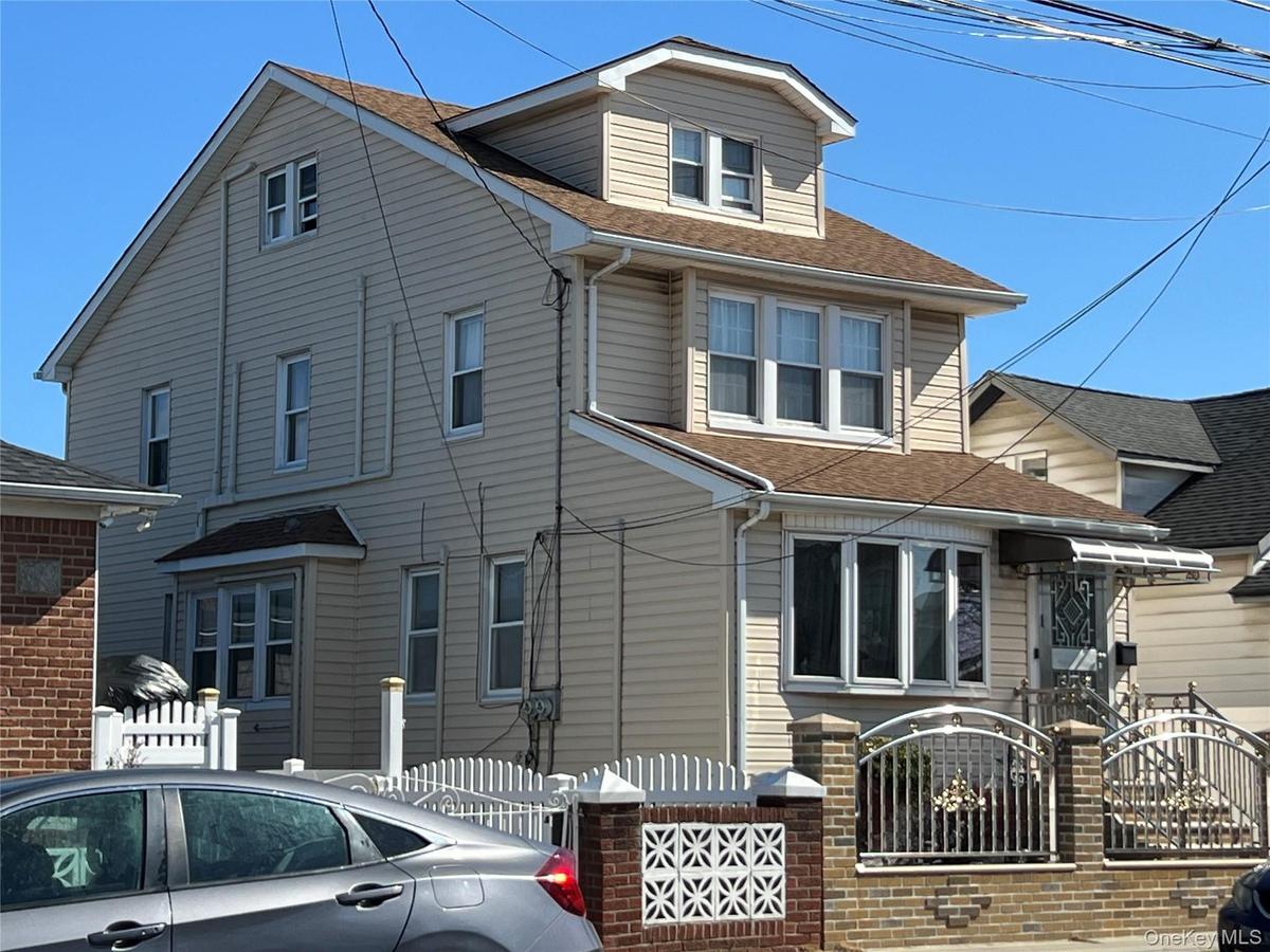 Traditional two-story residence with a dormer, featuring light-colored siding and a brown shingle roof