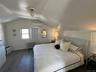 Room featuring sloped ceilings, wood-finish flooring, and a window with natural light