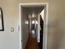 Long hallway with wood-finish flooring extending through multiple doorways