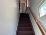 Carpeted staircase featuring a wood handrail and white wall paneling