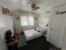 Room featuring a ceiling fan, wall-mounted air conditioning unit, and carpet flooring