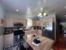 Kitchen featuring an island with a stone countertop, light wood cabinetry, stainless steel appliances, mosaic tile backsplash, and recessed lighting