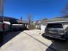 Expansive concrete patio area featuring a detached garage with a white sectional door, a covered outdoor structure, and a perimeter fence