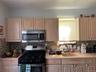 Kitchen featuring light wood-finish cabinetry, stainless steel microwave, stainless steel range, mosaic tile backsplash, and light pink countertops