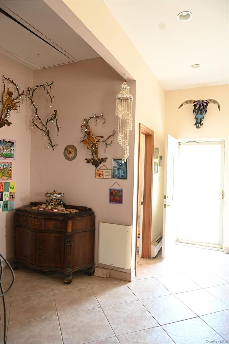 Corridor featuring light tile patterned floors and a baseboard radiator