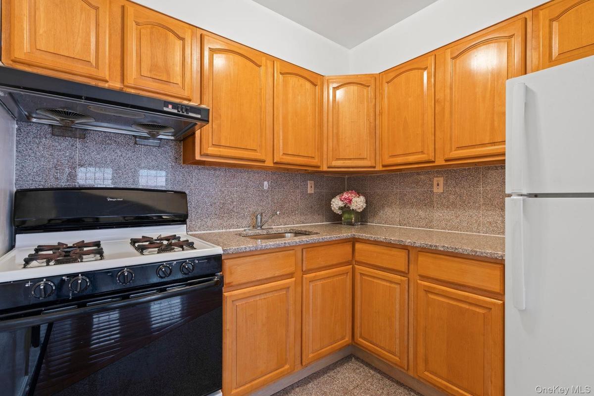 Kitchen featuring sink, gas stove, tasteful backsplash, white fridge, and range hood