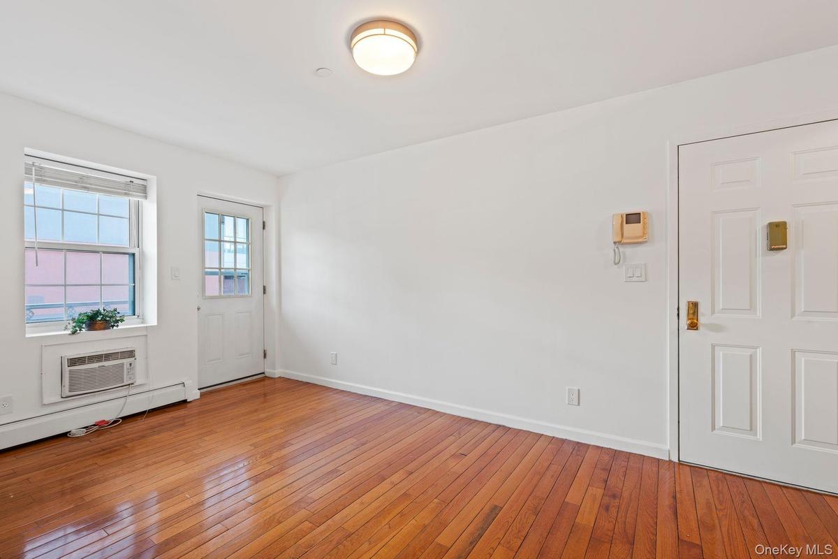 Entrance foyer featuring a baseboard heating unit, hardwood / wood-style flooring, and a wall mounted AC