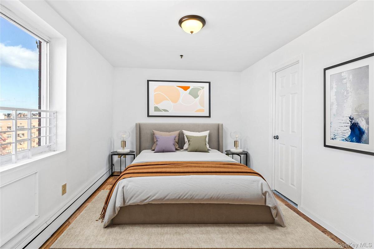 Virtual Staged Bedroom with a baseboard heating unit, multiple windows, wood finished floors, and baseboards