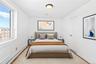 Virtual Staged Bedroom with a baseboard heating unit, multiple windows, wood finished floors, and baseboards