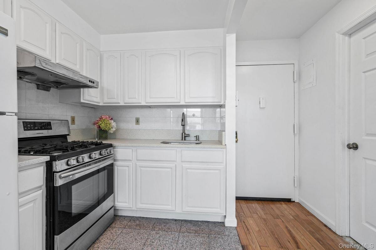 Kitchen with white cabinetry, sink, tasteful backsplash, and gas stove