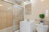 Full bathroom with toilet, vanity, shower / bath combination with glass door, and tile walls