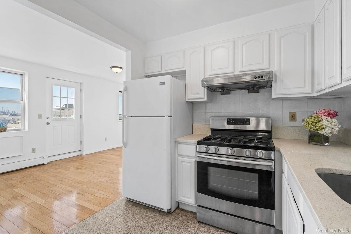 Kitchen featuring tasteful backsplash, white cabinetry, white refrigerator, gas range, and light hardwood / wood-style flooring