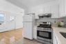Kitchen featuring tasteful backsplash, white cabinetry, white refrigerator, gas range, and light hardwood / wood-style flooring