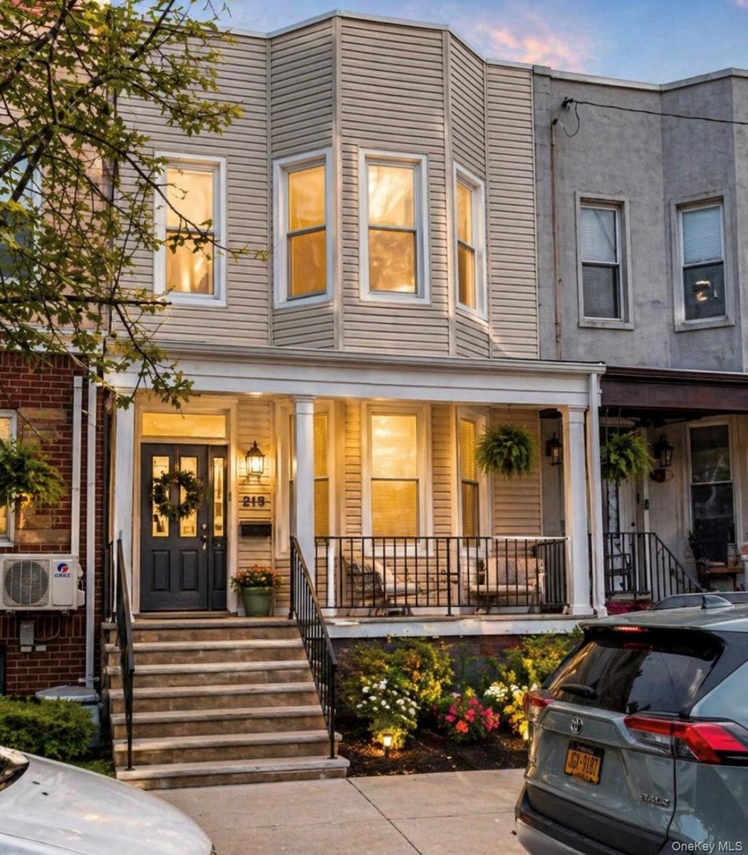 Inviting facade featuring a columned front porch, bay windows, and a dark entry door
