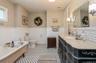 Bathroom featuring a clawfoot bathtub, black and white hexagonal tile flooring, a double vanity  and beadboard paneling