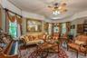 Formal living area featuring a bay window, wood-finish flooring, and a ceiling fan with integrated lighting