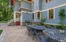 Expansive paver patio with a stone-clad outdoor kitchen area and a side entrance
