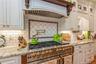 Professional-grade stainless steel range with brass-tone accents, set against a subway tile backsplash featuring an arabesque-patterned inset and a wa