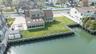 Waterfront property featuring a well-maintained bulkhead, a sunroom with multiple skylights, a patio area, and a paved driveway