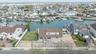 Waterfront property featuring a private boat dock, expansive backyard with manicured lawn, and a paved driveway