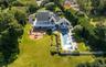 Expansive backyard featuring a rectangular swimming pool, a substantial paver patio with a built-in fire pit, and a spacious upper-level balcony