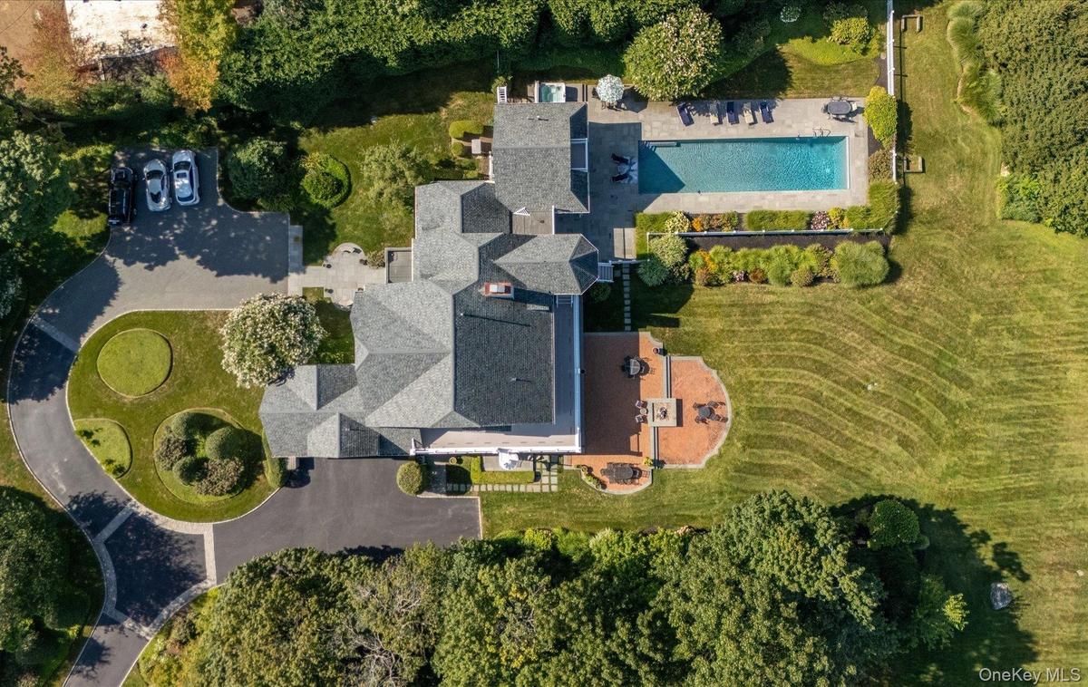 Extensive property featuring a multi-gabled main residence, a large swimming pool with surrounding patio, a curved driveway with landscaped islands, a