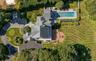 Extensive property featuring a multi-gabled main residence, a large swimming pool with surrounding patio, a curved driveway with landscaped islands, a