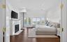 Spacious room featuring rich wood-finish flooring, a classic white mantel fireplace, and extensive white wainscoting