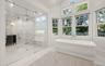 Soaking tub with a floor-mounted faucet, surrounded by multiple large windows and transom windows