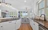 Kitchen featuring white cabinetry, dark stone countertops, a stainless steel sink with a matte black faucet, and subway tile backsplash
