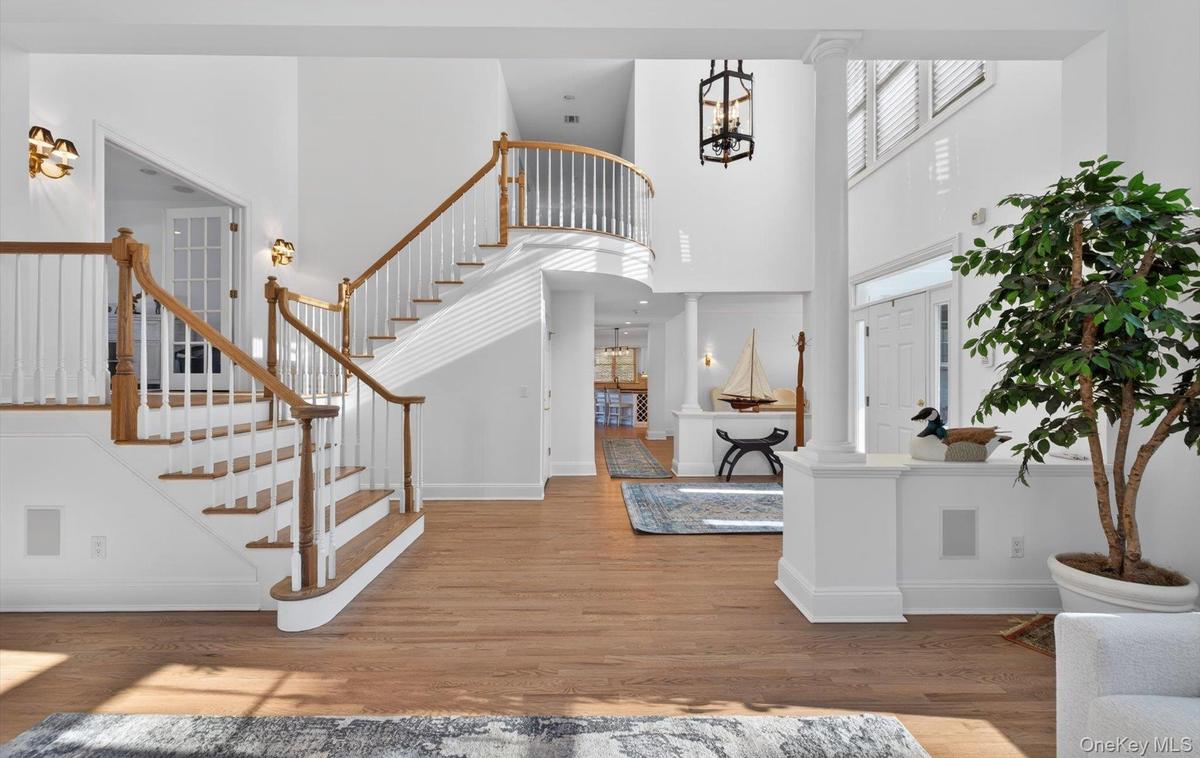 Grand foyer featuring a curved staircase with natural wood handrails and white balusters